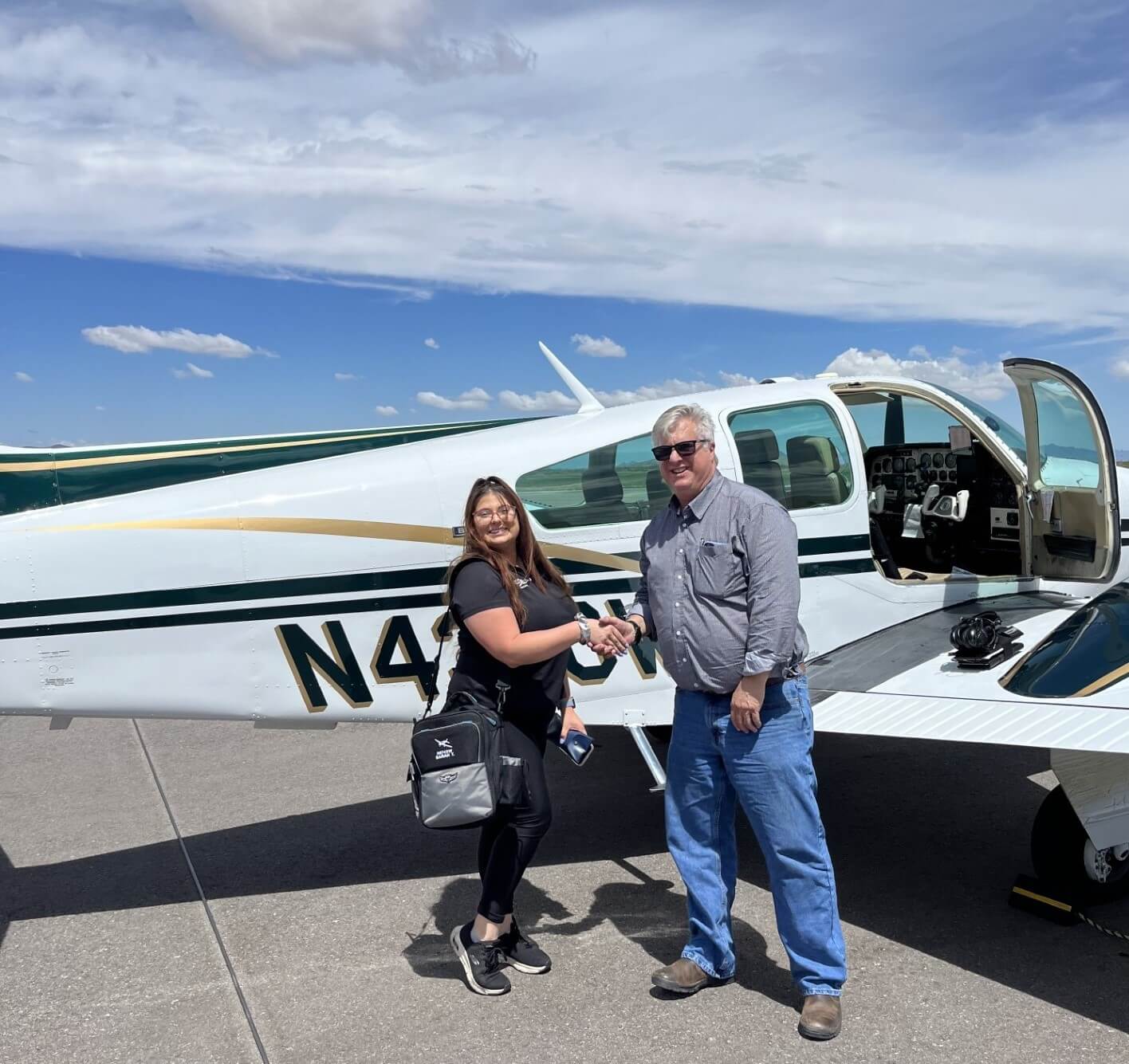 Sarah Tanis shaking Michael Garcia's hand standing in front of her plane. 